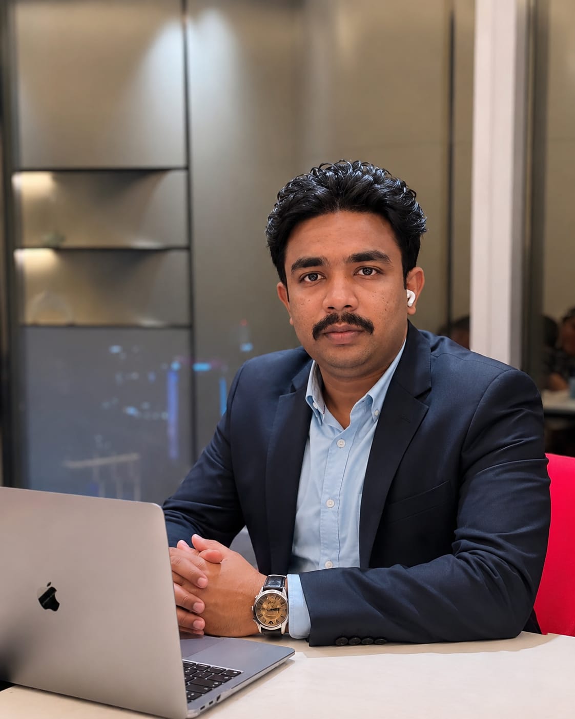 Nuhman Shibli seated at a business meeting with a laptop